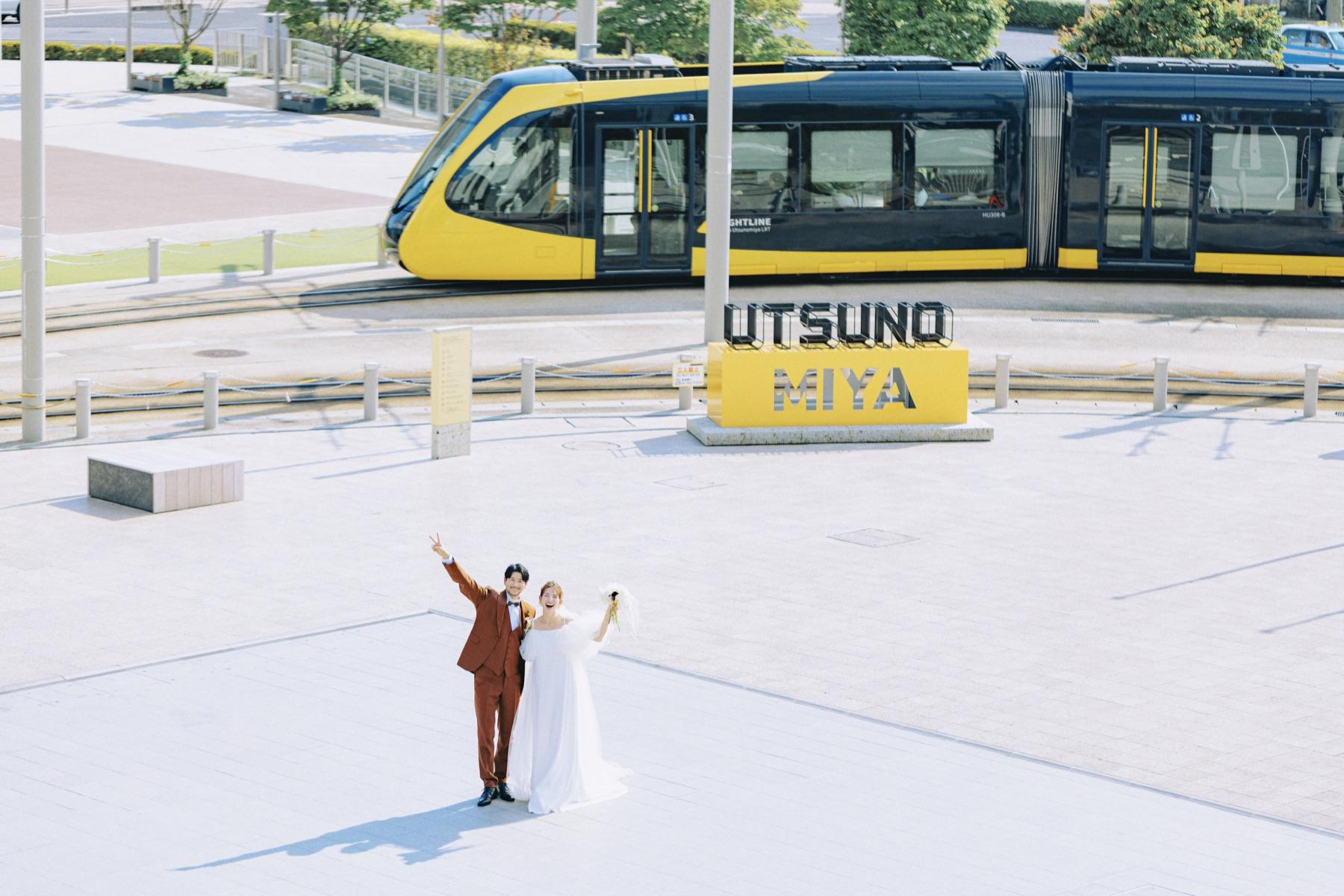 宇都宮駅東口、LRTの前で笑う二人
